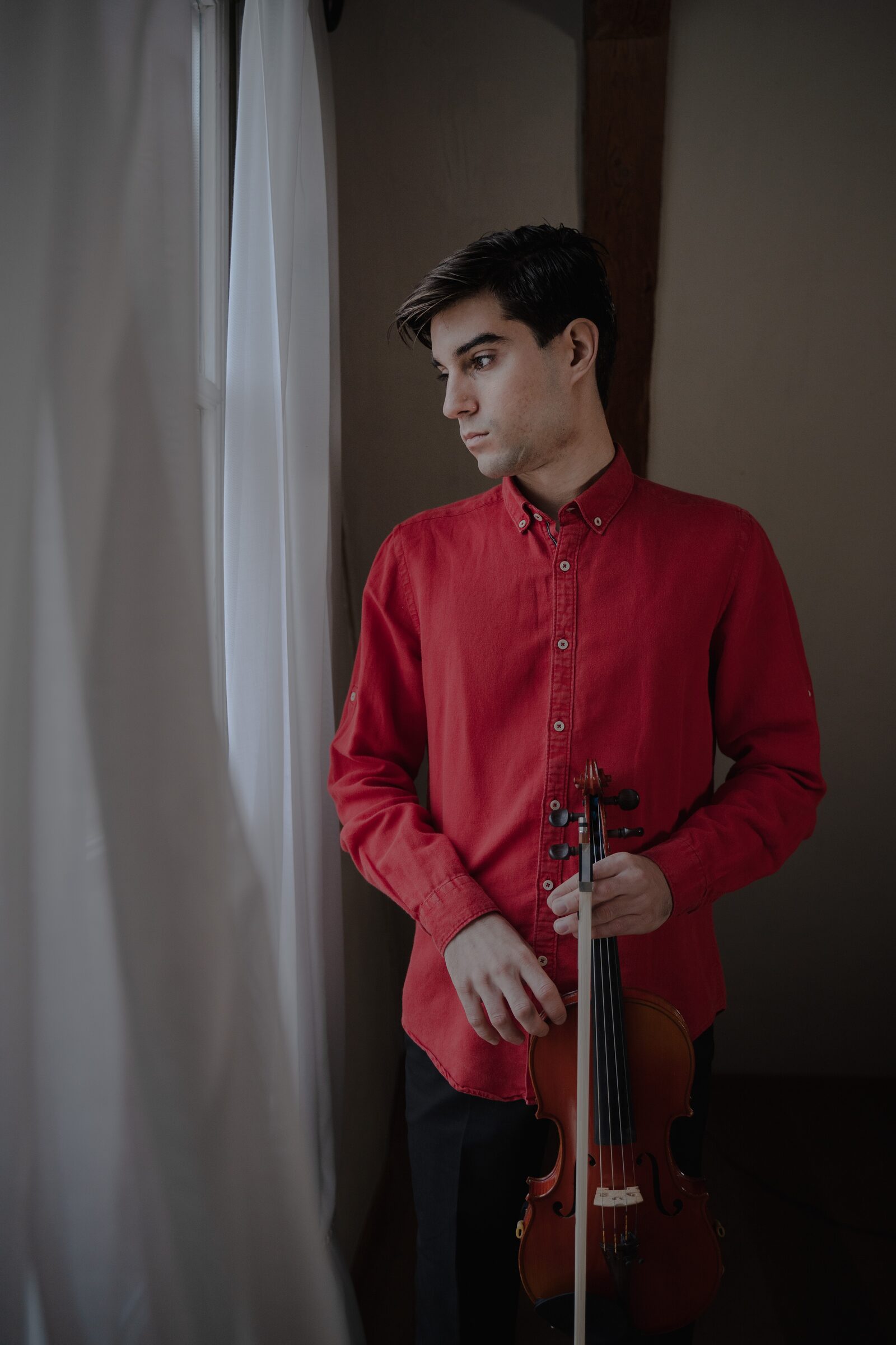 Alejandro Boix junto a una ventana, sosteniendo su violín